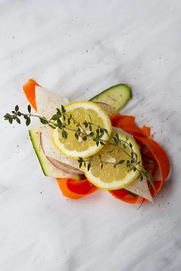 A fish fillet, lemon slices, and thyme sprigs have been added to the top of the vegetables.