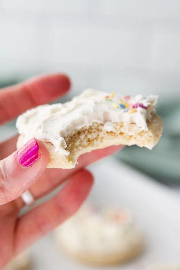 A frosted sugar cookie with a bite taken out.