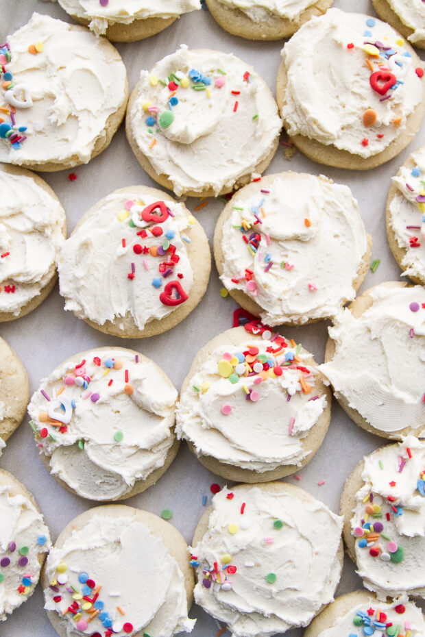 Round sugar cookies with white frosting and multi-colored sprinkles.