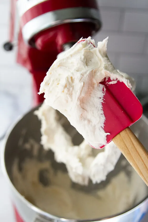 Finished fluffy white frosting on a red spatula.