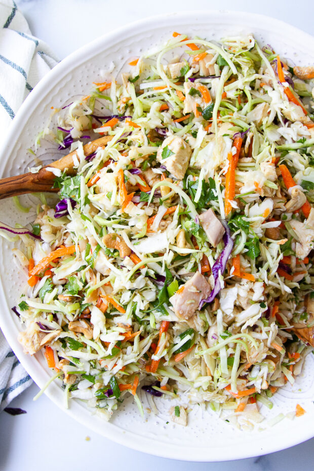 Large white salad bowl filled with ginger chicken salad -- chunks of cooked chicken and a lot of shredded vegetables.