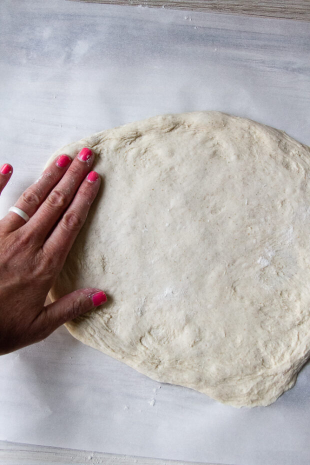 Dough spread out on a piece of parchment.