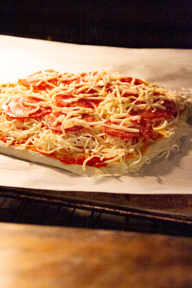 Parchment and pizza have been transferred to the preheated sheet pan in the oven.