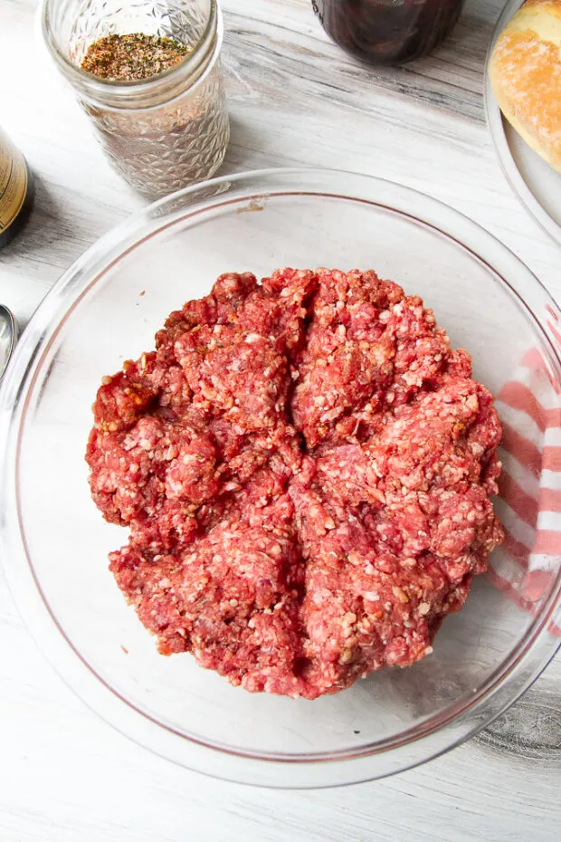 Meat roughly divided into six sections in the bowl after the ingredients have been mixed.