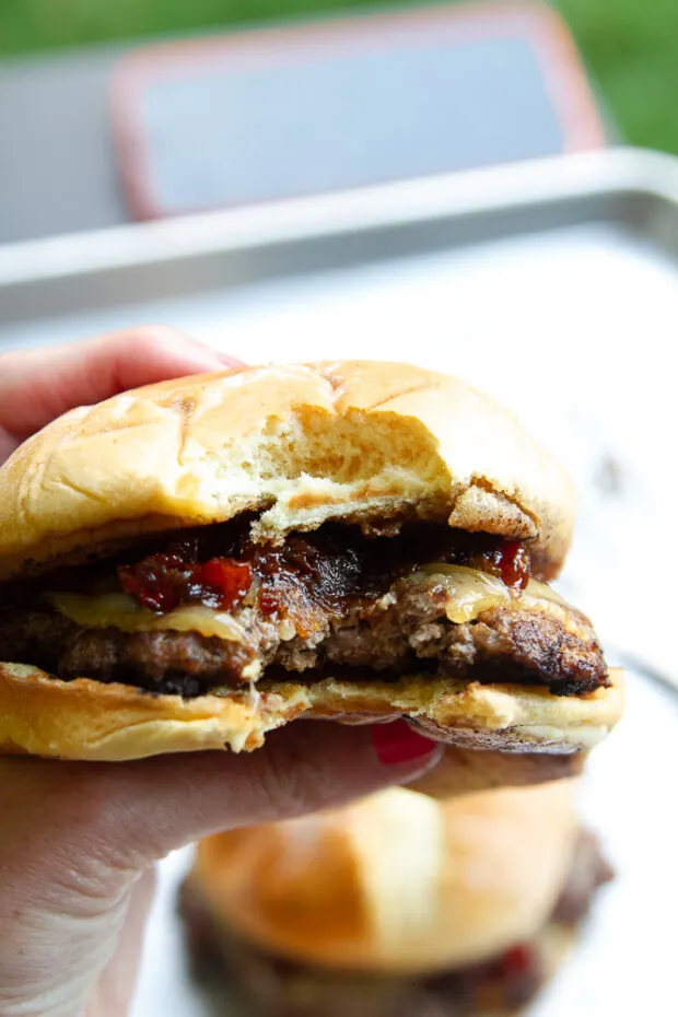 A bacon burger with a big bite taken out of it.