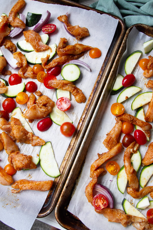 Two sheet pans with vegetables and shawarma-covered chicken.