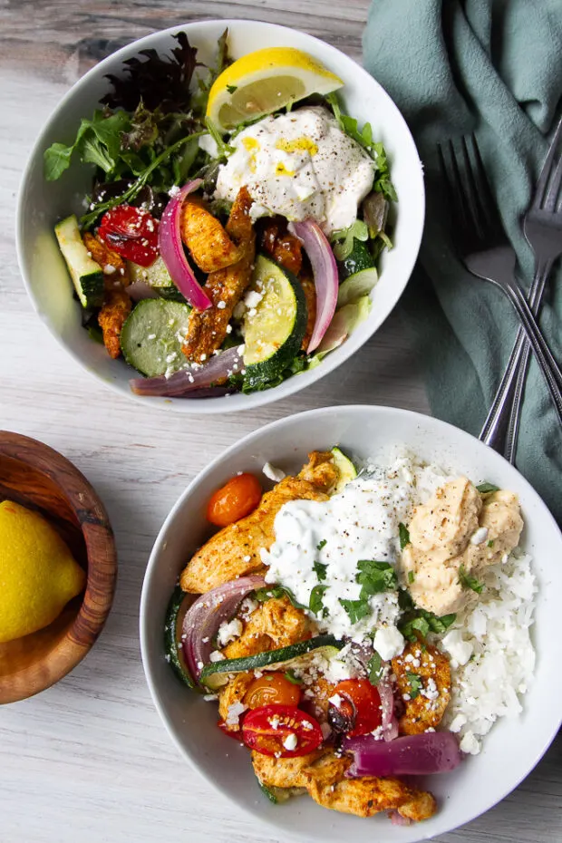 Two bowls - one with chicken shawarma & veggies with rice and one over salad greens.