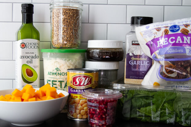 Ingredients for Harvest Grain Bowl: uncooked farro, butternut squash, spring greens, garbanzo beans, avocado oil, feta cheese, pecans, granulated garlic, pomegranate arils, balsamic vinaigrette, dried rosemary.