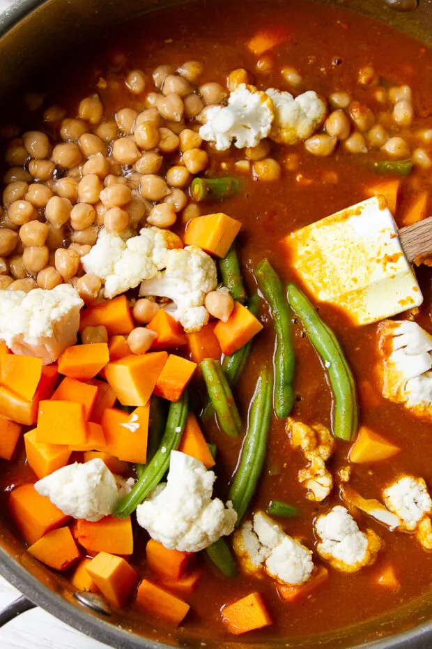 Vegetables and garbanzo beans have been added to the skillet.