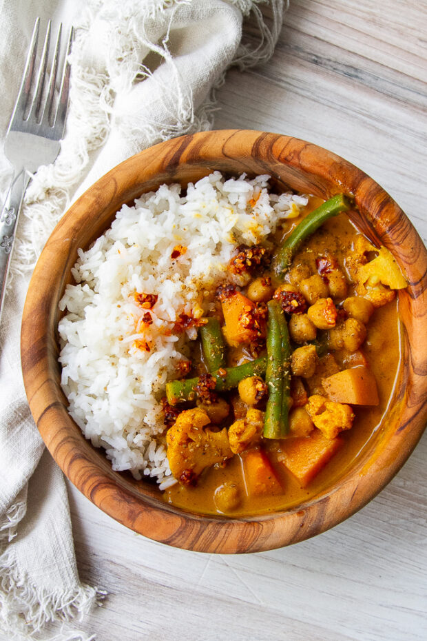 Wooden bowl with steamed rice and vegetarian pumpkin curry.