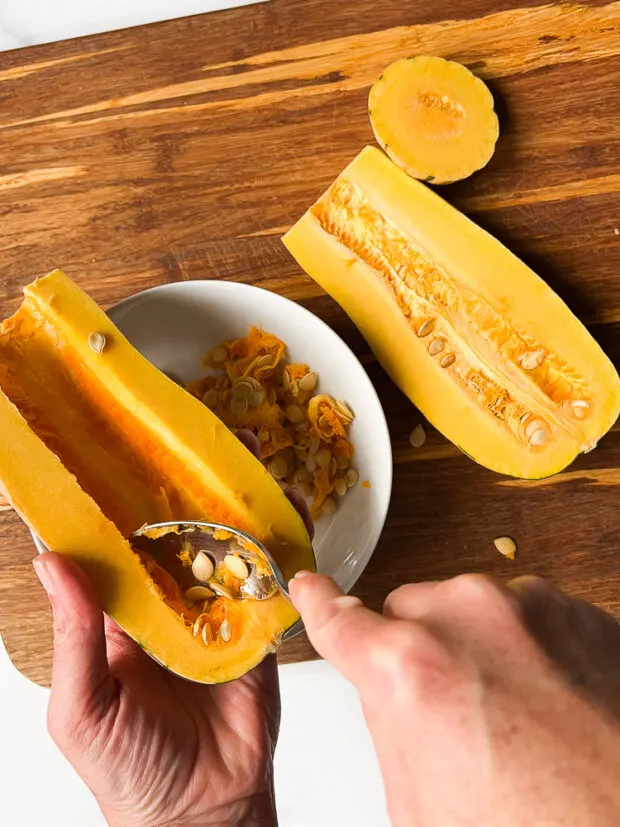 Scooping the seeds out of the squash halves.