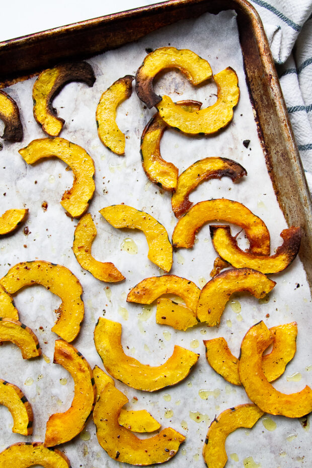 A sheet pan with roasted, golden brown delicata squash slices.