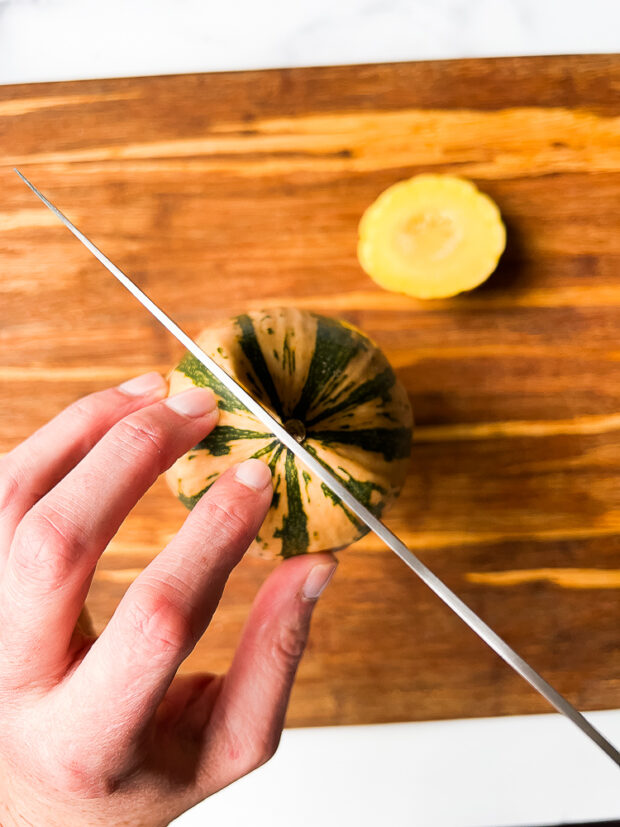 Placing the squash cut-side down and slicing in half downward from the other end. 