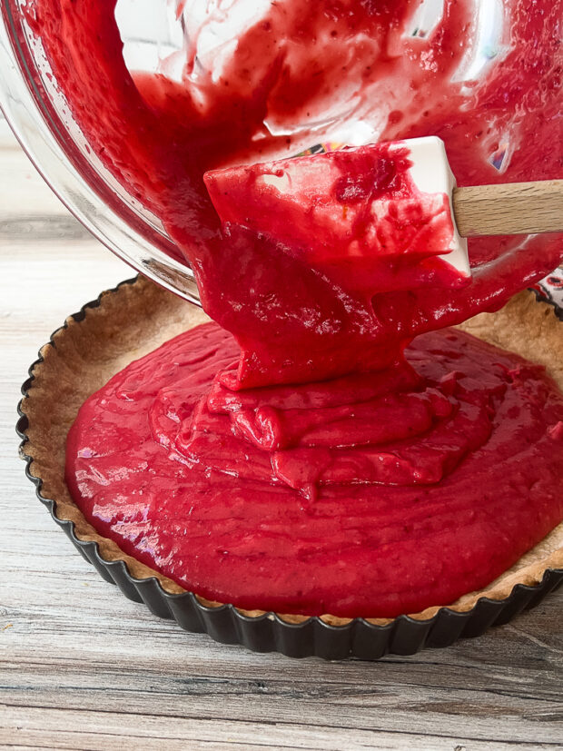 Filling has been blended with softened butter and is being transferred to the baked tart shell.