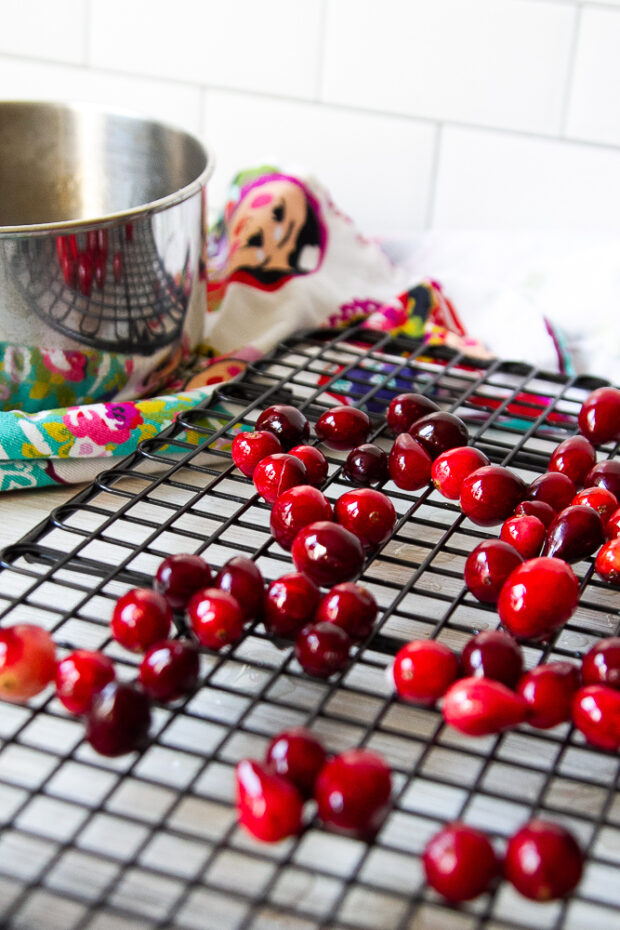 Making sugared cranberries by cooking the fresh cranberries in a simple syrup for a minute and now they're resting on a wire baking rack.