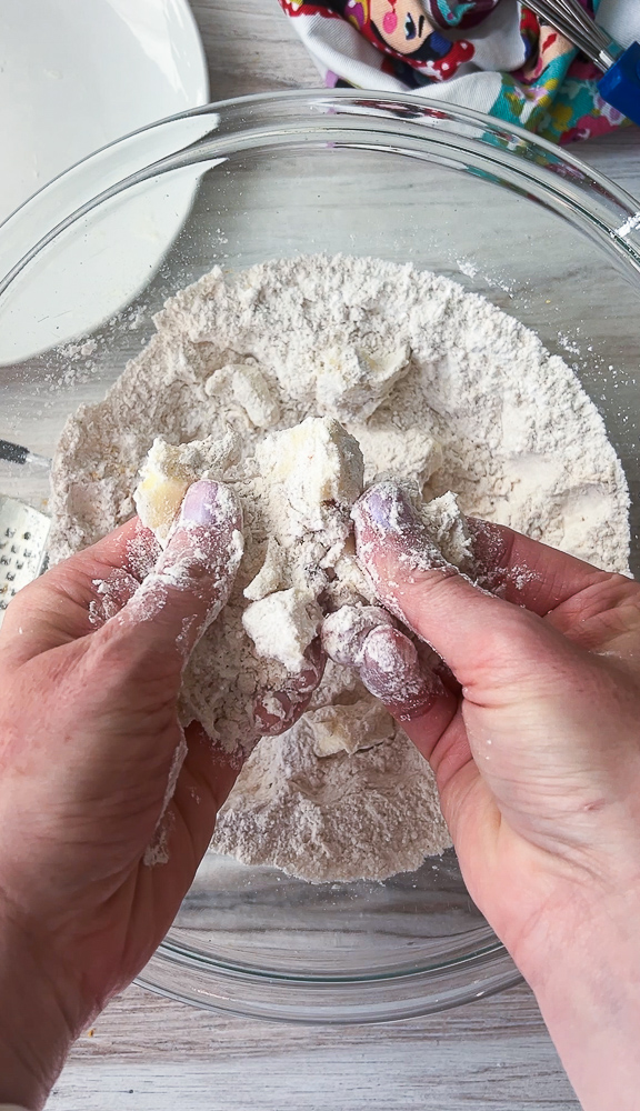 Fingers pinching the butter into the dry ingredients.