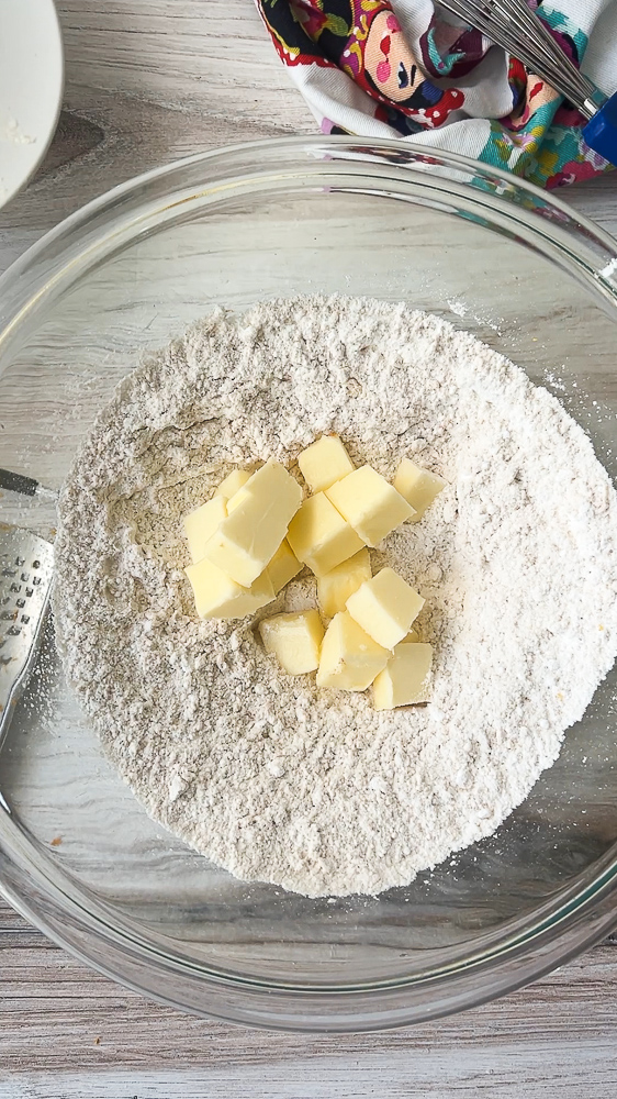 The beginnings of the crust: dry ingredients in a clear bowl with small cubes of soft butter on top.