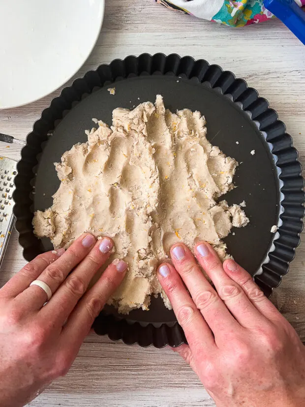 Tart dough beginning to be pressed into the tart pan.