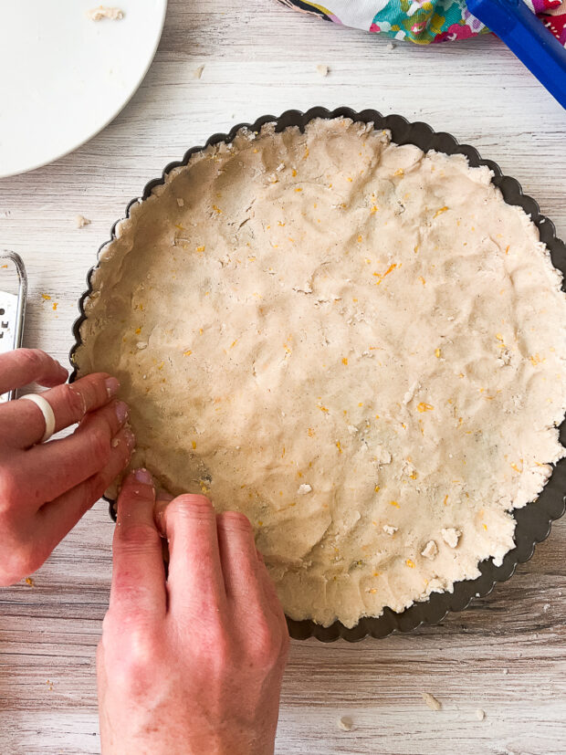 Pressing the dough into the sides of the tart pan.