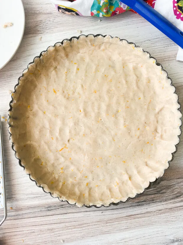 Dough is fully pressed into the tart pan and ready to bake in the oven.