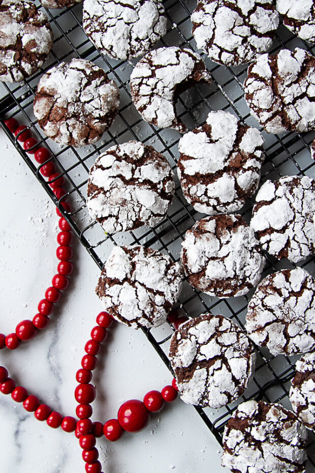 Baked chocolate crinkle cookies on a cooling rack. 