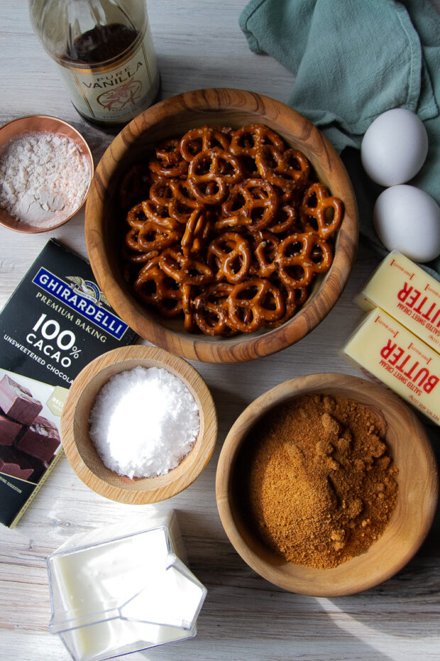 Ingredients set out for this chocolate tart: pretzels, butter, eggs, vanilla, gluten-free flour, unsweetened chocolate, coconut sugar, sea salt flakes, heavy cream.