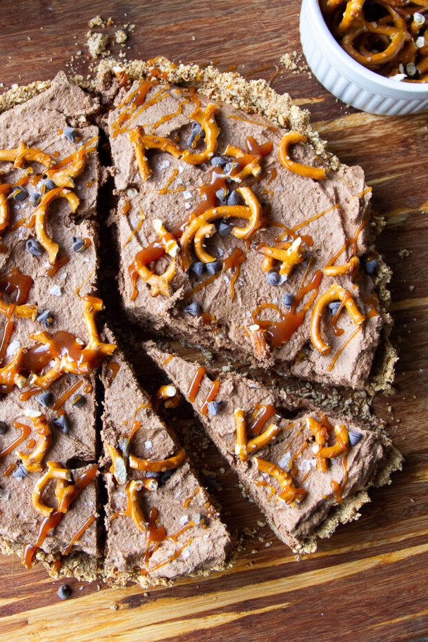 Salted Caramel Chocolate Tart on a wooden cutting board with a slice cut for serving.